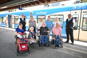 Die Personen stehen auf dem Bahngleis vor dem blauen Zug von GoAhead