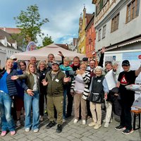 Eine große Gruppe von Menschen am Aktionsstand vor dem Freiheitsbrunnen. Sie werfen vor Freude die Arme in die Luft. 
