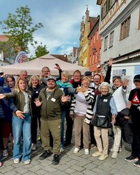 Eine große Gruppe von Menschen am Aktionsstand vor dem Freiheitsbrunnen. Sie werfen vor Freude die Arme in die Luft. 