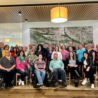 Die Teilnehmenden stehen, bzw. sitzen vor einer großen Luftbildaufnahme von Regensburg. 